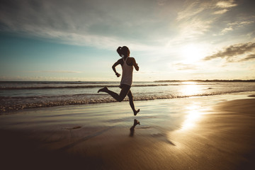 Fitness woman runner running on sunset beach