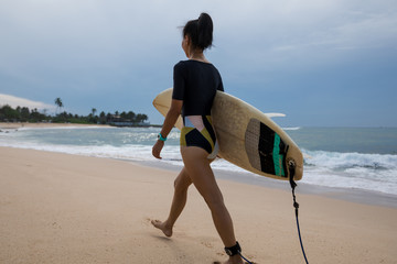 Surfer woman walking with surfboard on the beach