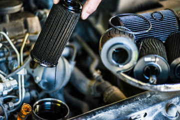Mechanic changing old or used oil filter from car engine. Vehicle service or maintenance. - obrazy, fototapety, plakaty
