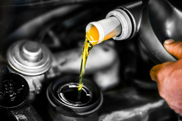 Mechanic changing used or old oil. Car service or manintenance. Close up of  pouring liquid into...