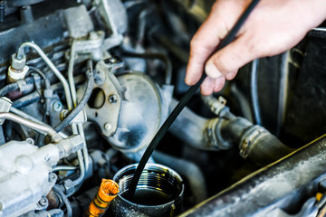 Close-up of mechanic hand draining or removing old oil. Car maintenance of vehicle.