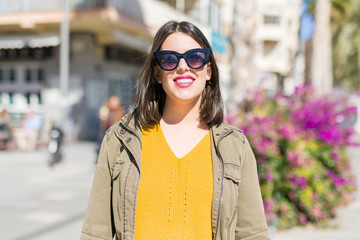 Beautiful young woman smiling cheerful walking on the street on a sunny day wearing sunglasses, casual pretty girl at the town