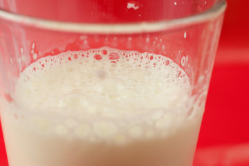 Glass of fresh milk on a red background
