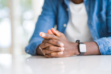 Close up of crossed hands of african man over table