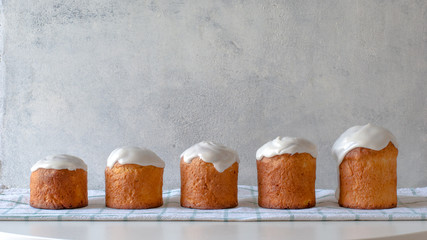 Five pieces of Easter cakes in a row in ascending order from small to large. Festive bread on the background of light gray concrete wall. Concept of growth, increase.