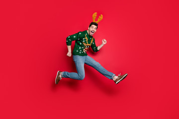 Full size photo of funny guy jumping high run speed to x-mas discounts shopping wear green knitted pullover with deer ornament isolated red color background
