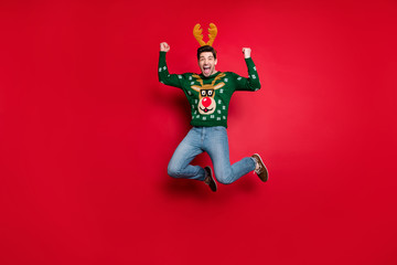 Fototapeta na wymiar Full body photo of funky guy jumping high excited with x-mas discounts wear knitted green pullover with ugly deer ornament isolated red color background