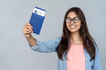 Happy excited young adult Indian woman student holding passport with airplane flight ticket...