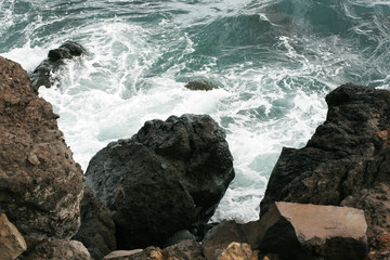 Volcanic stones on ocean shore, cold clean water, waves, Madeira island, Portugal