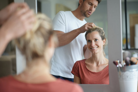 hairdresser at home styling young woman