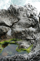 Volcanic stones on ocean shore, cold clean water, waves, Madeira island, Portugal