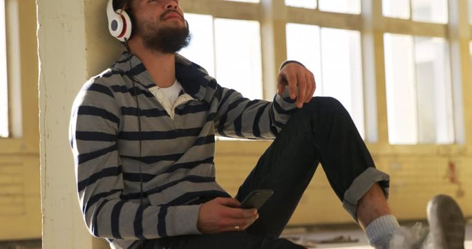 Young man listening to music in empty warehouse