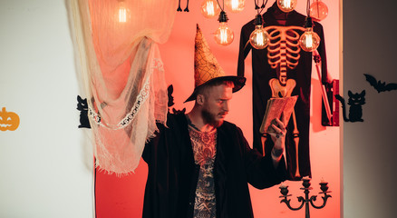 Halloween man with pumpkin in darkness. Handsome man in wizard costume hat for Halloween on...