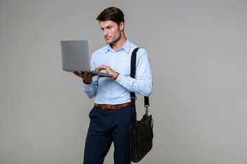 Image of caucasian businessman in office clothes holding laptop computer