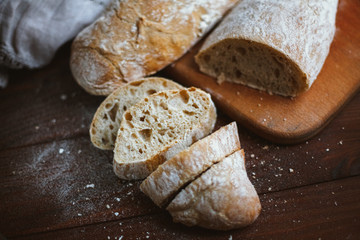 Chiabatta homemade bread. Fresh baked bread on a kitchen board and wooden background. White bread and chopped slices.
