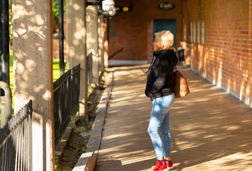 Trendy woman in jeans standing waiting