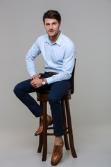 Full length portrait of happy young businessman sitting on chair