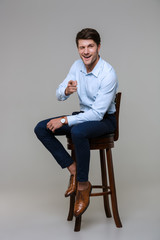 Full length portrait of handsome young businessman sitting on chair