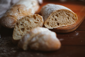 Chiabatta homemade bread. Fresh baked bread on a kitchen board and wooden background. White bread and chopped slices.