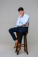 Full length portrait of successful young businessman sitting on chair