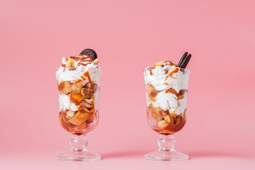 Sweet dessert in glass with biscuit and whipped cream on pink bsckground, selective focus and blank space