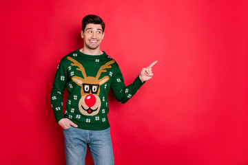 Portrait of funny funky brown hair man in deer reindeer theme sweater point index finger at copy...