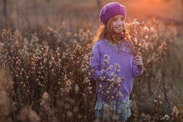 Portrait of adorable little girl outdoors on nature in the autumn field