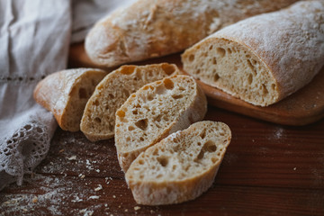 Chiabatta homemade bread. Fresh baked bread on a kitchen board and wooden background. White bread and chopped slices.
