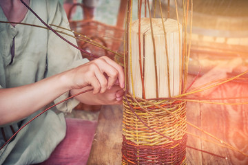 A man weaves a basket of willow branches. Master basketmaker creates at work in the Studio.
