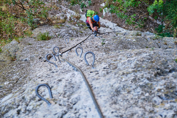 Strong, fit woman climbing a vertical section on via ferrata at Turda gorge (Cheile Turzii) Romania...