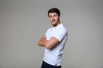 Image of joyful brunette man smiling at camera with hands crossed