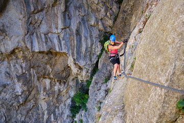 Female tourist traversing a via ferrata section in Turda gorge (Cheile Turzii) Romania, with...