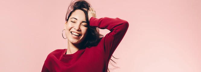 panoramic shot of attractive asian woman in red sweater smiling isolated on pink