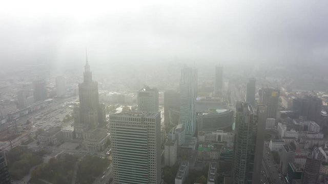 Drone shot at skyscrapers and buildings in the fog. Warsaw Poland. Aerial view on the silhouettes of modern office buildings in the fog at morning. 4K Shot Drone.