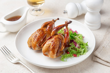 Whole roasted quail on white plate