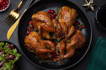 Roasted quail with cranberry and thyme on black plate for Christmas dinner, - obrazy, fototapety, plakaty