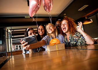 Group of girls surprise their girlfriend with a birthday party at a coffee shop and making selfie.