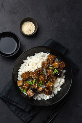 roasted teriyaki eggplant with rice in black bowl, top view