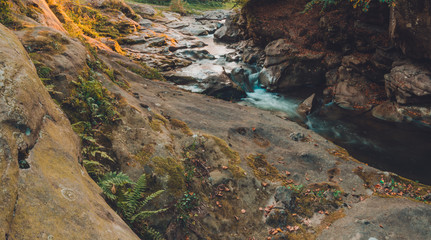 Strong water stream in the high mountain area surrounded by stones with small moss islands in the water body.