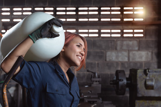 Young diverse Asian woman delivering water bottle on her shoulder - Female Hispanic delivery agent arriving at factory with wholesale inventory order - immigrant, low skilled and workplace concept