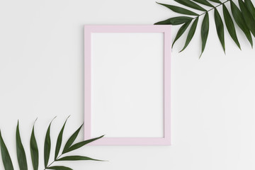Top view of a pink frame mockup with palm leaf decoration. Portrait orientation.