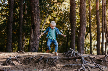 Emotional portrait of a happy and cheerful little boy, running after a friend laughing while playing on a walk in the park. Happy childhood. Summertime. Summer vacation. Positive emotions and energy