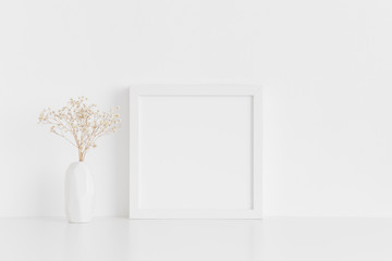 White square frame mockup with a gypsophila in a vase on a white table.