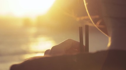 Happy young woman enjoyng drinking cocktail at sunset by the sea on island coast