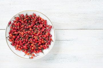 Berries of red rose hips useful for health on a wooden surface