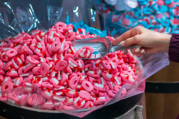 Woman hand with scoop taking colorful delicious marmalade jelly candies on counter of shop,...