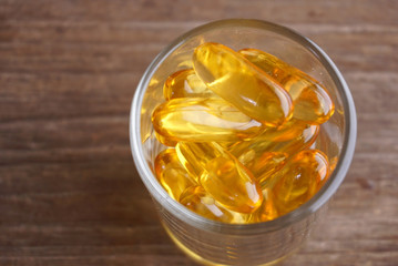 Close up group of fish oil carry on glass lay on wood table