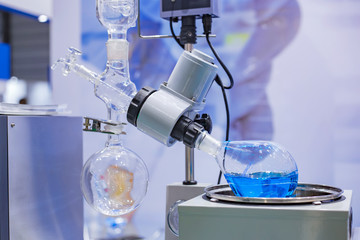 Laboratory rotary evaporator - homogenization process - rotating chemical flask for evaporate solvent from blue liquid at pharmacy factory or medical exhibition. Pharma, chemistry and science concept