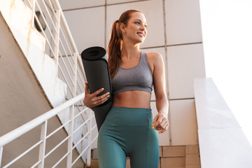 Smiling fit young sportsgirl walking down a staircase