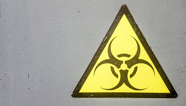 Biohazard sign symbol biohazard warning, black yellow triangle signage macro on gray metal wall